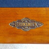 Brunswick logo plate on rail of pool table