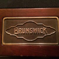 Metal Brunswick stamp on Cromwell pool table rail.