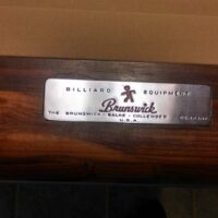 BBC logo plate on the end rail of a Brunswick Balke Collender Centennial pool table.