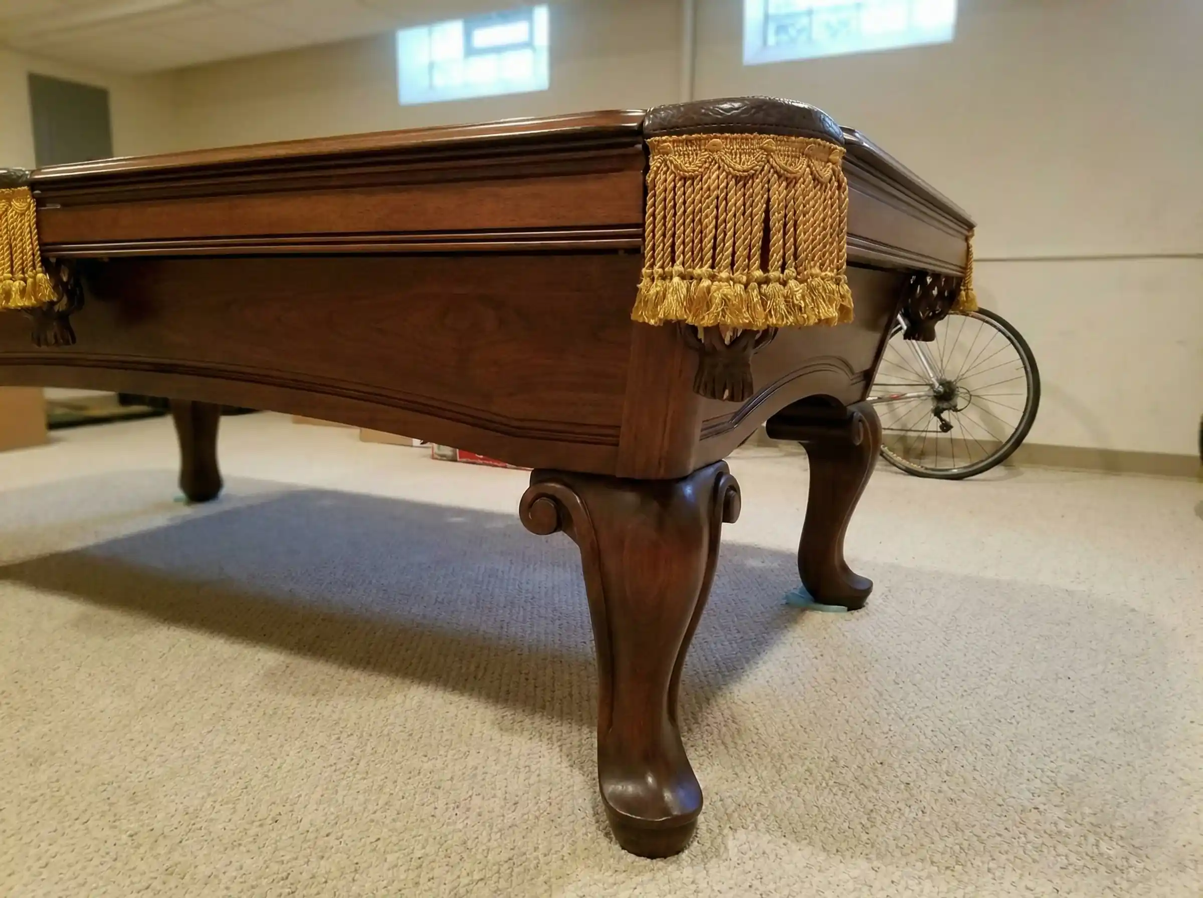 Leg assembly on an AMF Highlander used pool table, showing drop pockets lined with leather and fringe.