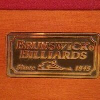 Brunswick Billiards metal logo embossed on the rail of this Dominion pool table.
