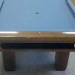 End view of a Brunswick Bridgeport pool table in a honey finish.