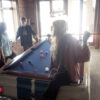 group of teens playing pool on a a limited edition Shelby GT-350 car pool table.