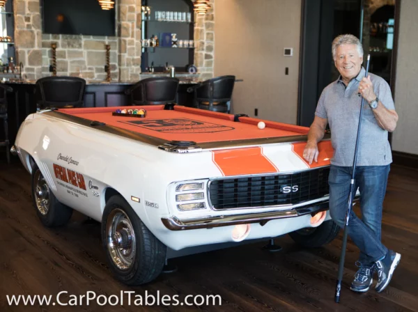 Mario Andretti standing next to his signature car pool table.